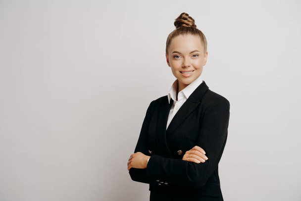 Woman executive in dark suit standing sideways - Fotoğraf, Görsel