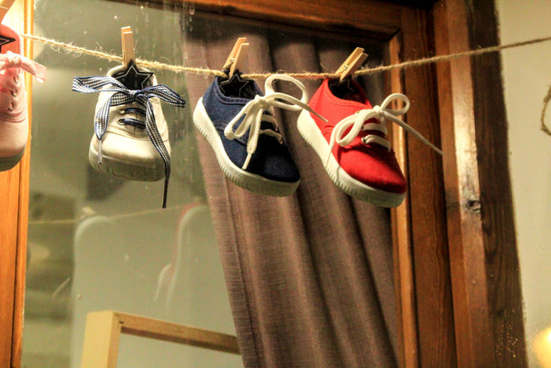 スペイン、アリカンテのアルテアでショーケースに列にぶら下がっている子供用の靴 - 写真・画像