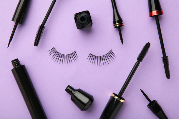 Close up of black eyeliners and mascara brush on purple background. Top view. - Фото, зображення
