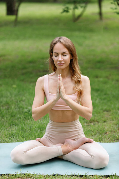 Woman in lotus pose namaste yoga in summer park - Foto, imagen