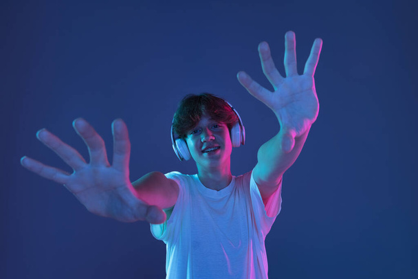 Caucasian young man isolated on blue studio background in neon. Concept of human emotions, facial expression. - Fotó, kép