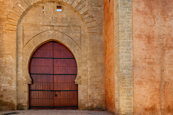 Arabic door Bab laalou in the wall of the medina of Rabat in Morocco. Reddish varnished wood and stone plastered in ocher tones - Photo, Image