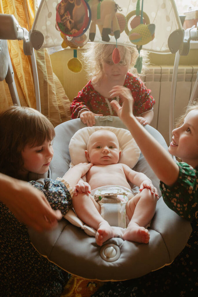 Children gathering in room together siblings around the cradle - Photo, Image