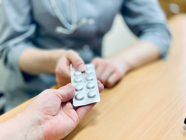 Az orvos vényköteles tablettákat javasol a betegnek. Az orvos a gyógyszert tabletták formájában írja elő.. - Fotó, kép