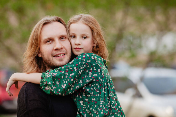 Vater und Tochter umarmen sich und blicken in die Kamera - Foto, Bild