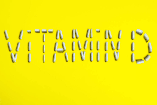 Pills capsules word text VITAMIN D on yellow background. Medical medicine concept. - Φωτογραφία, εικόνα