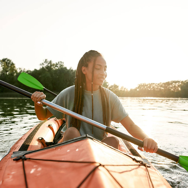 Adventurous young woman paddling kayak on a lake together with her boyfriend on a summer afternoon - Foto, immagini