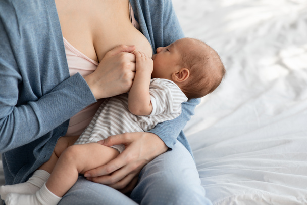 母乳育児の利点.母親から母乳を吸う愛らしい空腹の新生児の胸 - 写真・画像
