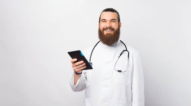 Retrato del joven médico alegre sonriendo y sosteniendo la tableta. - Foto, imagen