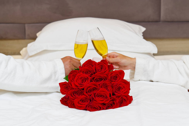 Strauß roter Rosen auf dem Bett in einem Hotelzimmer für die Flitterwochen. Romantisches Treffen der Gäste im Hotel. - Foto, Bild