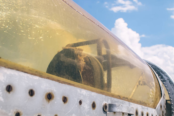 Zbliżenie kabiny pilota myśliwca wojskowego. Na szkle widoczne jest pęknięcie, które z wiekiem żółkało. Zlikwidowany sprzęt wojskowy. Siedzenie pilota samolotu - Zdjęcie, obraz