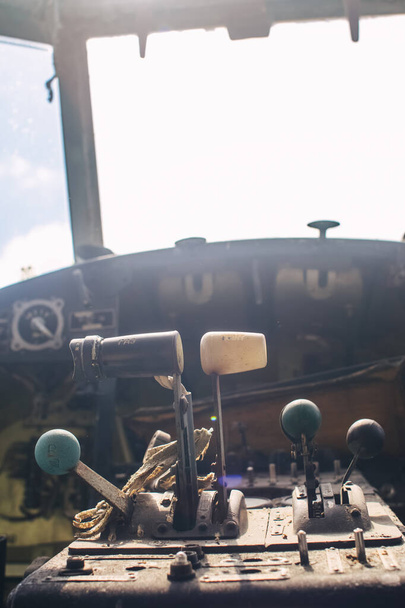 A close up of the cockpit of a vintage airplane. The steering wheel, dashboard, seat and climb levers are visible. Decommissioned aircraft. Everything is broken and damaged from time to time. - Photo, Image