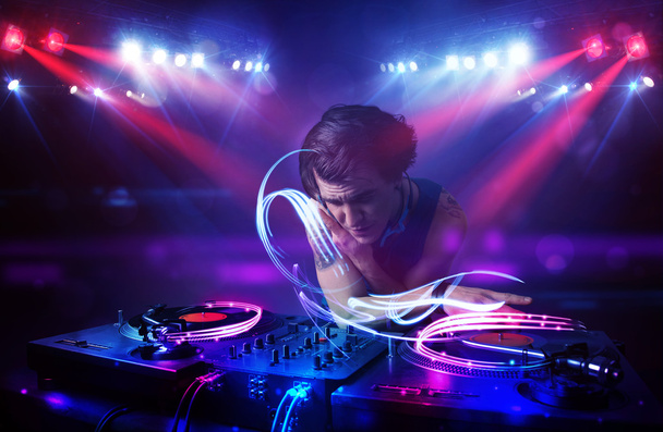Disco jockey tocando música con efectos de haz de luz en el escenario
 - Foto, imagen