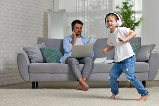 kid dancing and busy dad working with laptop at home - Foto, immagini