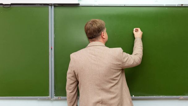 Math teacher writes chalk on blackboard copy space. - Foto, Imagen