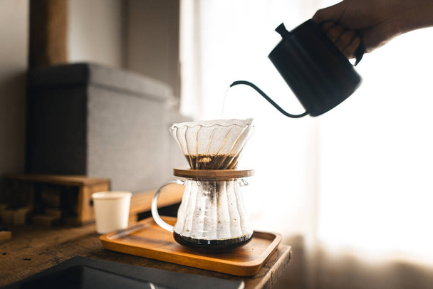 Tiputa kahvia, barista kaataa vettä kahvimaahan suodattimella, keittää kahvia - Valokuva, kuva