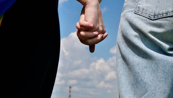 Lesbians hold hands close up on the sky background - Photo, Image