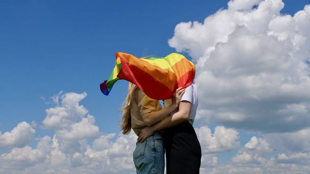 Lesbians hugging and holding an LGBT flag - Фото, изображение