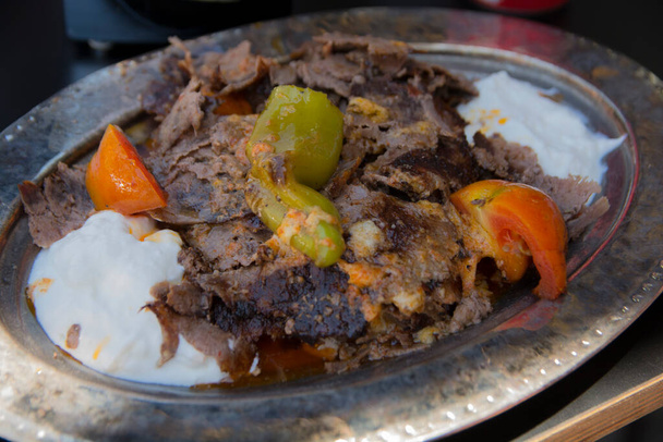kebap skender, jedno z najpopularniejszych dań Turcji, cienko i starannie pokrojone grillowane jagnię zwieńczone gorącym sosem pomidorowym nad kawałkami chleba pita - Zdjęcie, obraz