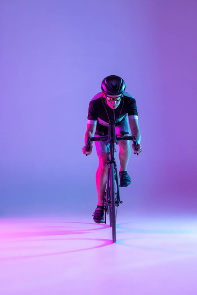Cyclist riding a bicycle isolated against neon background - Zdjęcie, obraz