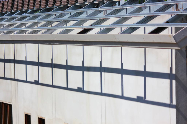 fény és árnyék tető ragasztó acél szerkezet cement falon az építési területen - Fotó, kép