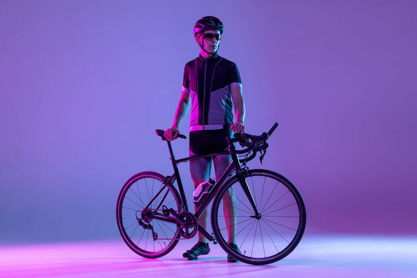Cyclist riding a bicycle isolated against neon background - Foto, Imagem