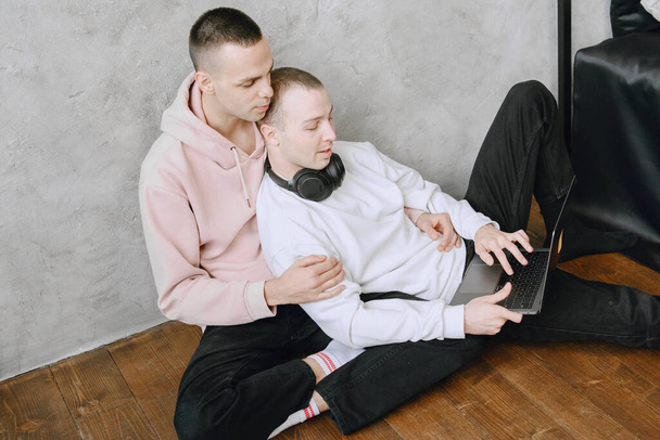 Gay couple consulting their travel plans together with a laptop - Fotó, kép