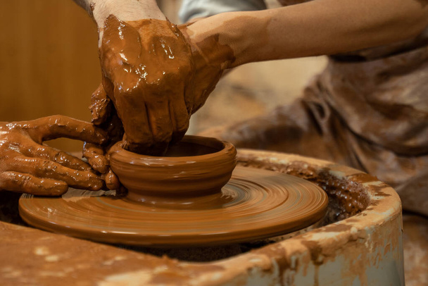 Hands of the skilled master Potter and woman hands, training of the woman to production of pottery on a Potter wheel - 写真・画像