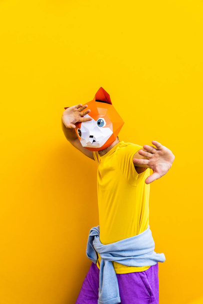Cool man wearing 3d origami mask with stylish colored clothes - Creative concept for advertising, animal head mask doing funny things on colorful background - Foto, imagen