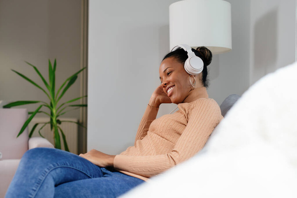 African girl wearing headphones watching and listening videos on laptop - Foto, Imagen