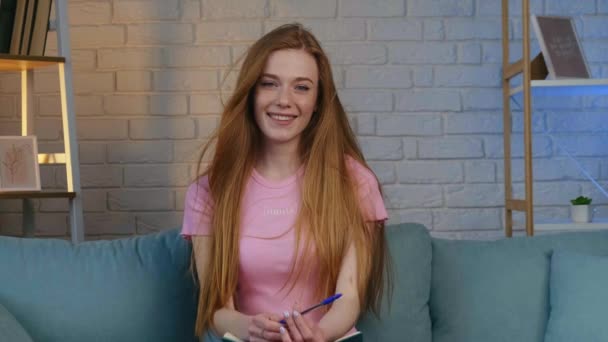 Ginger woman with freckles is smiling at camera while holding a book - Footage, Video