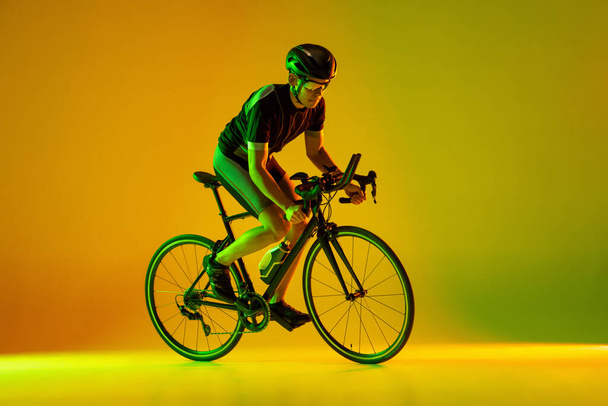 Cyclist riding a bicycle isolated against neon background - Fotó, kép