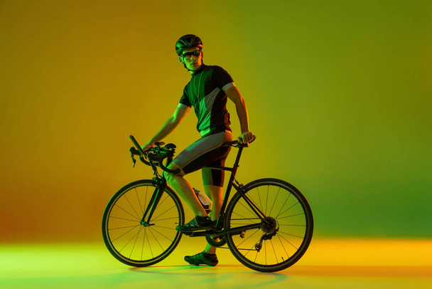 Cyclist riding a bicycle isolated against neon background - Foto, immagini