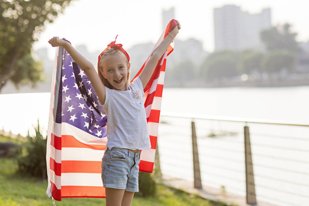 Patriotic holiday. Happy family, mother and daughter with American flag outdoors on sunset. USA celebrate independence day 4th of July. - Valokuva, kuva