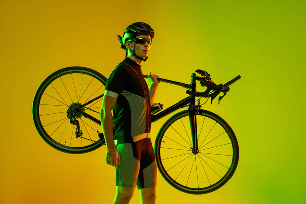 Cyclist riding a bicycle isolated against neon background - Photo, Image