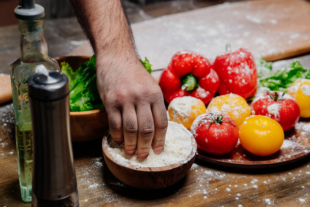 hand takes flour from a wooden bowl. ingredients for cooking.  - Φωτογραφία, εικόνα