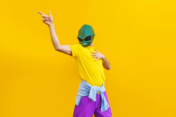 Cool man wearing 3d origami mask with stylish colored clothes - Creative concept for advertising, animal head mask doing funny things on colorful background - Foto, Imagen
