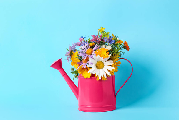 Pink watering can with beautiful flowers on light blue background - Photo, Image