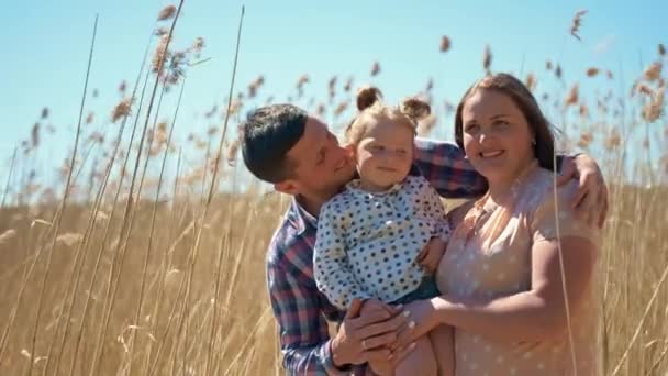 Joyeux jeune couple avec une petite fille dans les bras sur la nature sur le fond de roseaux - Séquence, vidéo