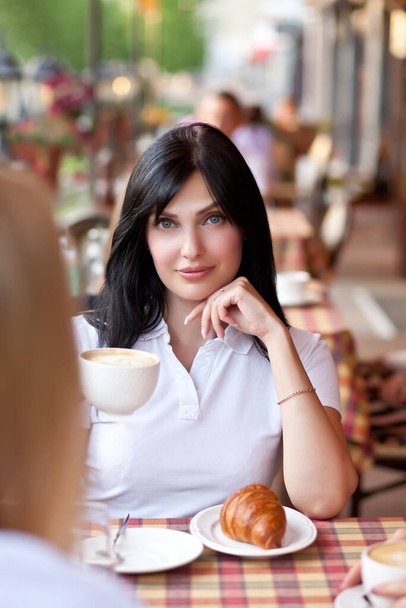 Smiling brunette woman at cafe drinking coffee with croissant. Communication and friendship concept. - Valokuva, kuva