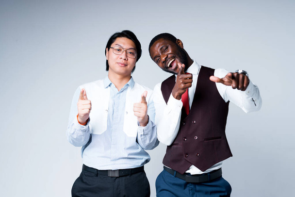 Happy african american and asian business people smiling and throwing thumbs up while looking at the camera - Foto, afbeelding