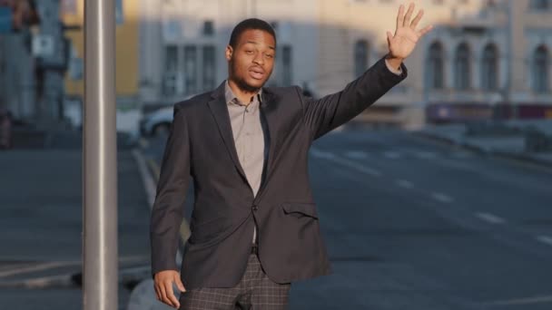 Çekici Afrikalı Amerikalı öğrenci, takım elbiseli genç adam dışarıda taksi bekliyor. Modern iş adamı ya da müdür büyük şehirde araba sürücüsüne işaret veriyor. Taksi servisi kavramı - Video, Çekim