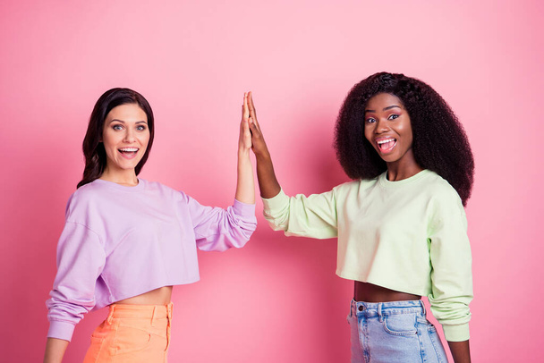 Photo of two excited ladies raise hands clap five wear cropped sweatshirt isolated yellow color background - Fotó, kép