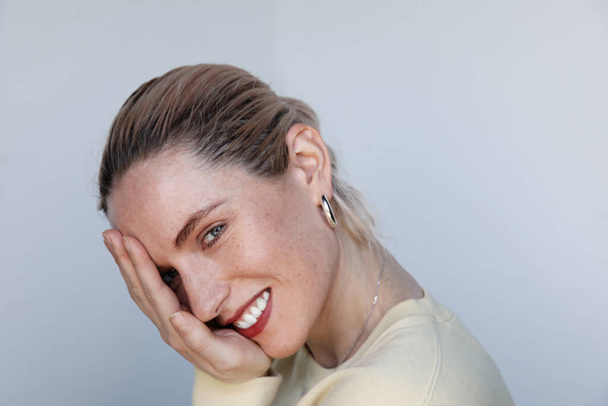 Portrait of a young happy woman smiling on white wall, skin care and health. - Foto, afbeelding
