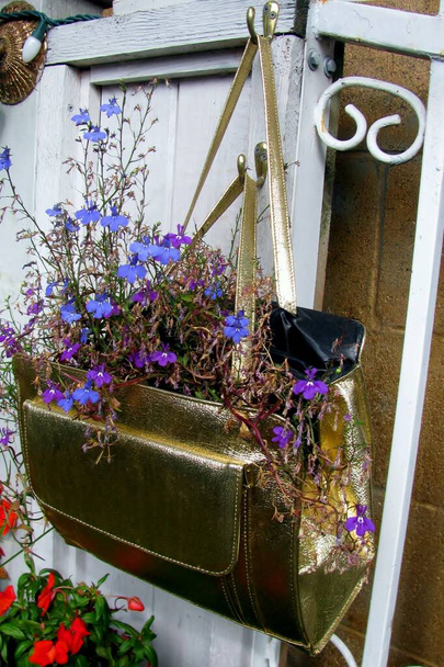 Stara torebka przebudowywana jako sadzarka wisząca na podwórku ogrodzenia. - Zdjęcie, obraz