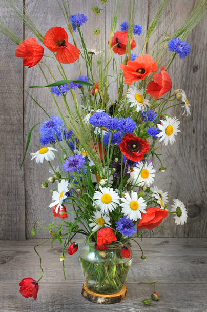 Beautiful bouquet with poppies and wild flowers in the basics on a gray wooden background. Selective focus - Photo, Image