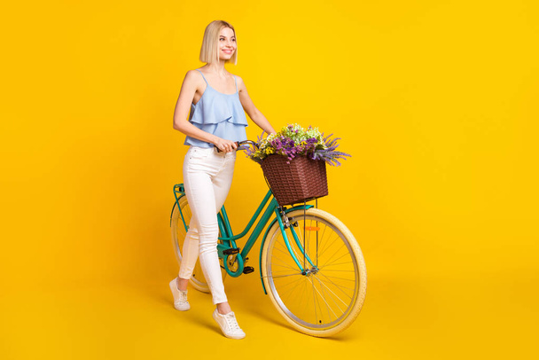 Full body profile photo of cheerful blond hair lady ride bicycle wear top pants isolated on yellow background - Φωτογραφία, εικόνα