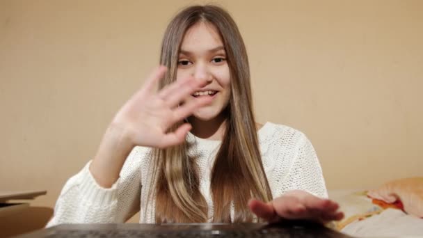 Šťastný usměvavý dospívající dívka mluví s přítelem prostřednictvím videokonference na notebooku doma. vzdálená práce a vzdělávání - Záběry, video