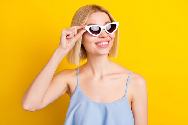Photo of cheerful blond short hair lady look empty space wear spectacles blue top isolated on yellow color background - Φωτογραφία, εικόνα