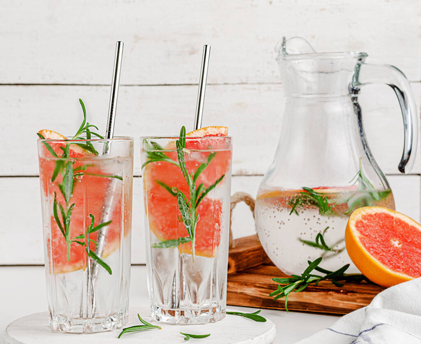 Healthy citrus beverage with grepefruit and rosemary on white wooden background. Infused water - Photo, Image